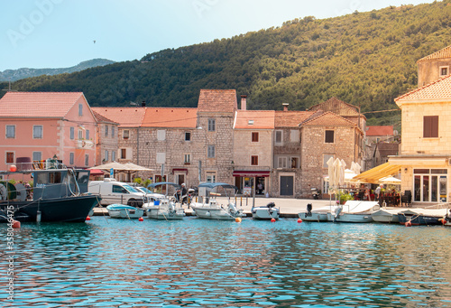 View of a small town center of the town Starigrad at Hvar island. Old small boats in the water as life goes on in a small village on a warm summer day