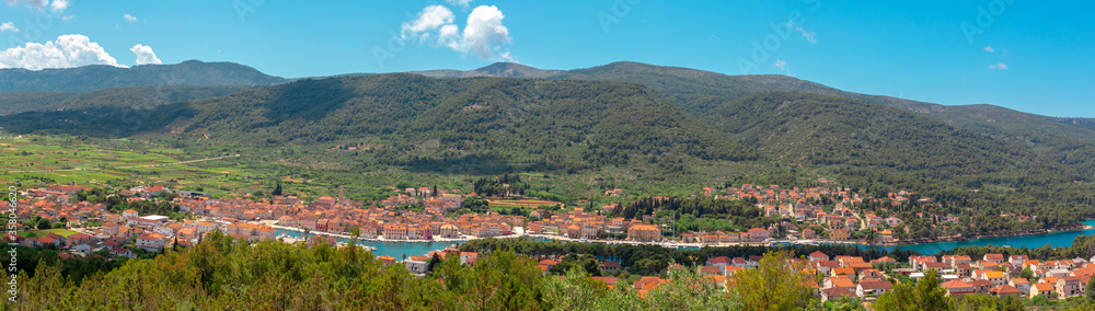 Wide picturesque panorama of Starigrad town on the island of Hvar. Seen from a nearby hill. Town buildings seen stretching from the harbour entrance to the city center
