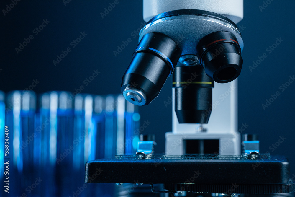 Close up of laboratory microscope with set of test tubes with blue liquid Close up of laboratory microscope with set of test tubes with blue liquid