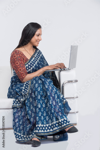 Woman in traditional sari writing e-mails on laptop