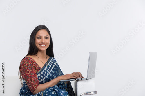 Canvas Print Woman in traditional sari writing e-mails on laptop