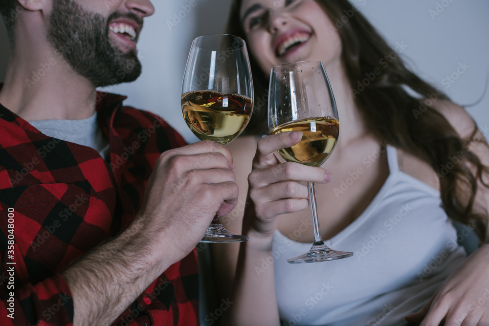 selective focus of young couple laughing while holding glasses of white wine selective focus of young couple laughing while holding glasses of white wine