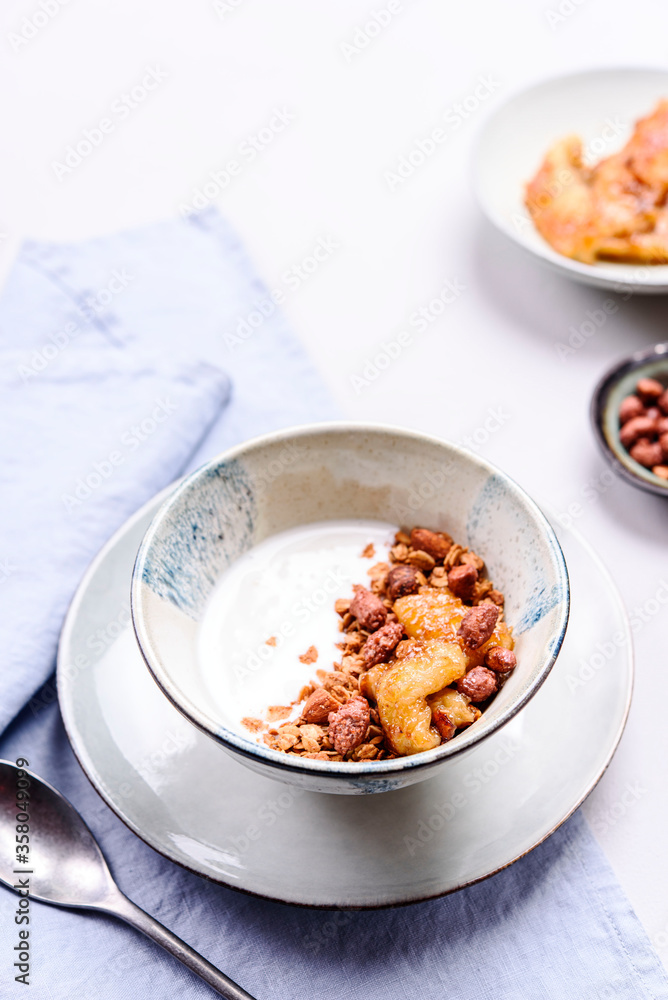 Healthy breakfast yogurt bowl with granola and caramelized bananas and nuts on grey concrete background. Selective focus Healthy breakfast yogurt bowl with granola and caramelized bananas and nuts on grey concrete background. Selective focus