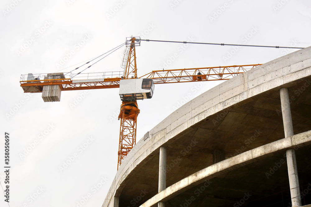 Fototapeta premium Construction crane near concrete building.