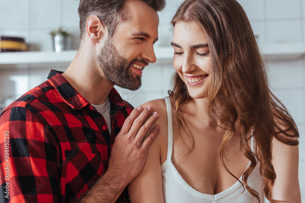 smiling man touching shoulder of happy young girlfriend in kitchen smiling man touching shoulder of happy young girlfriend in kitchen