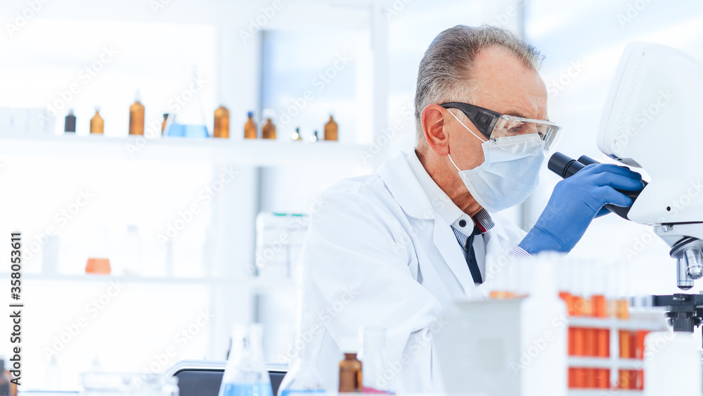scientist in a protective mask conducts research in the laboratory. scientist in a protective mask conducts research in the laboratory.