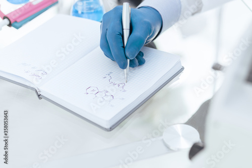 close up. female scientist writing research results in a notebook.