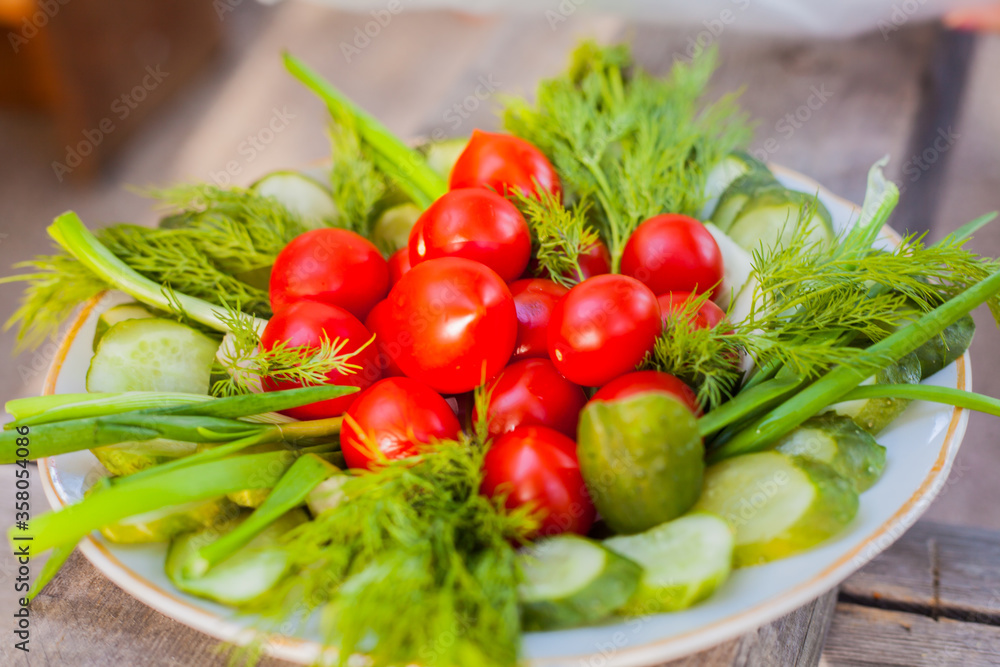 Small tomatoes with cucumbers and lettuce on the background of wood. Small tomatoes with cucumbers and lettuce on the background of wood.