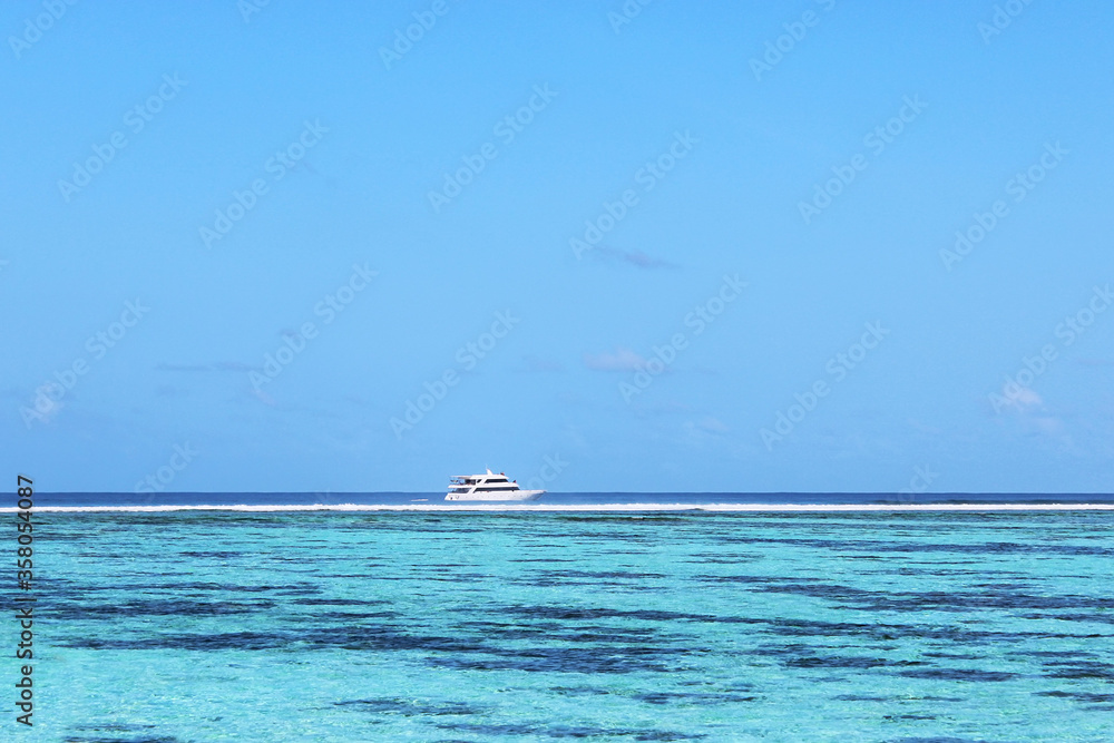 Motor boat sailing in azure waters on Indian ocean near Nalaguraidhoo island. Speed boats used as a main transport to bring people to resorts on Maldives islands. Tropical sunny vacation. Soft focus