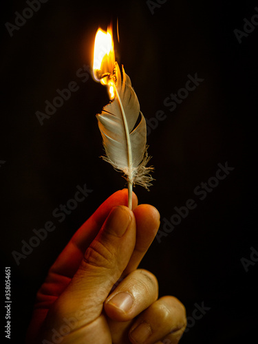 hand holding feather in fire