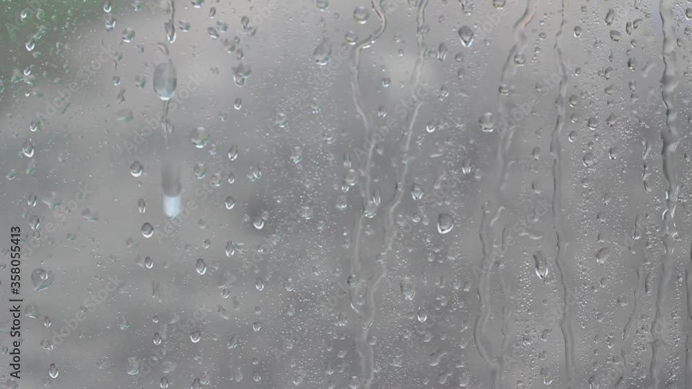 Drops of water flow down the gray glass Drops of water flow down the gray glass