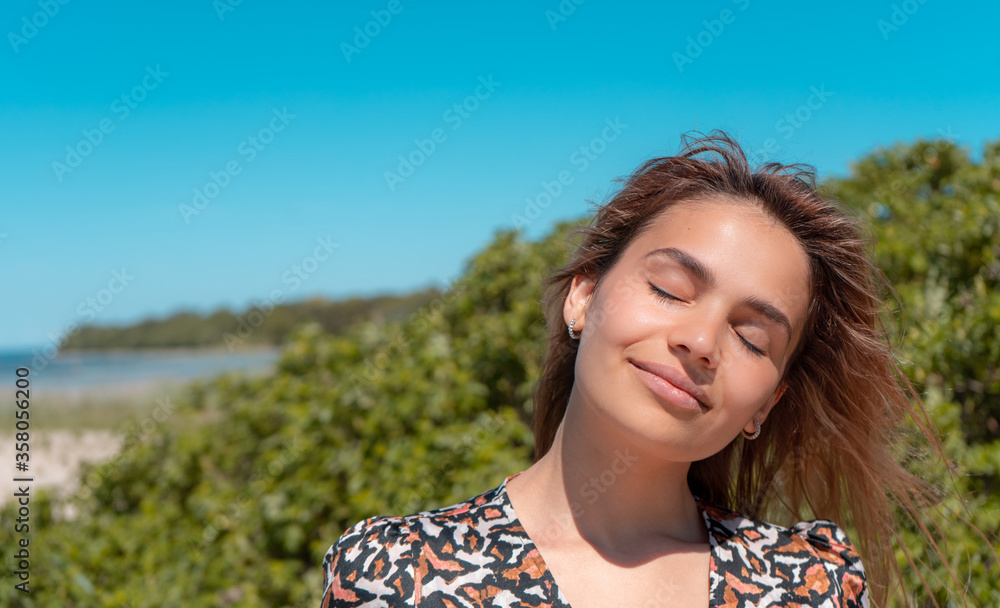 Beautiful female smiling on the beach. Portrait of handsome woman laughing on a sunny day on the sand 