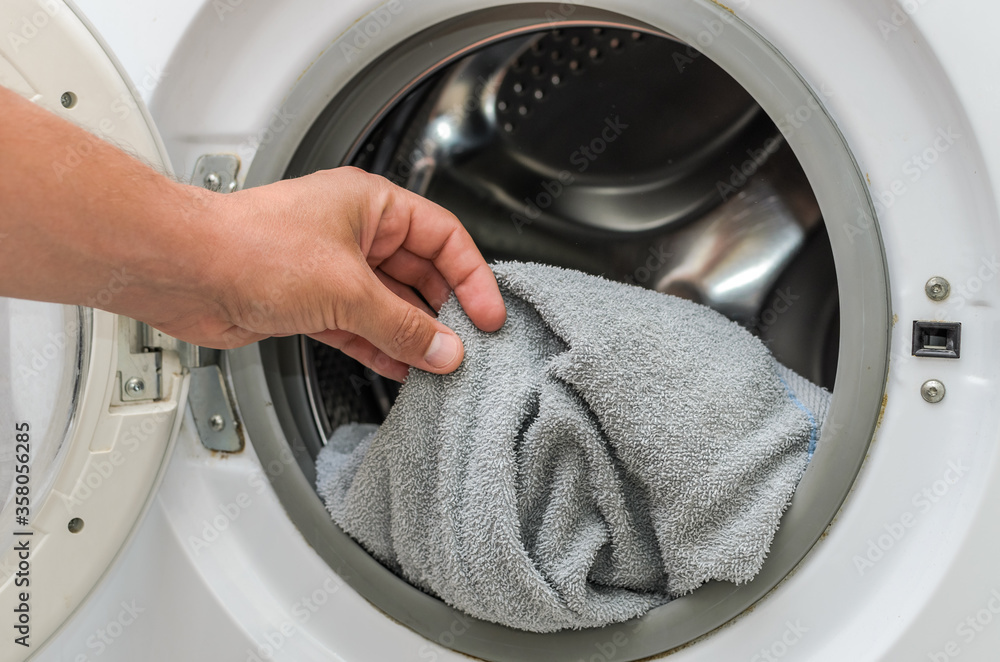 Housekeeper throws dirty clothes into the washing machine Housekeeper throws dirty clothes into the washing machine