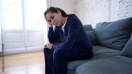 Young lonely attractive latin woman crying on couch feeling sad tired and worried suffering depression isolated at home. Mental Health and lockdown, stress, unemployment and solitud concept.