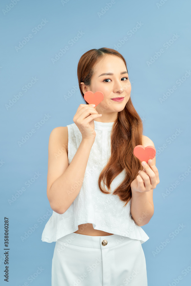 Photo of a beautiful happy young pretty woman posing isolated over blue wall background holding hearts. Photo of a beautiful happy young pretty woman posing isolated over blue wall background holding hearts.
