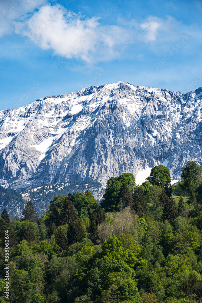 Green forest, snowy mountain peaks and sky with clouds, Wetterstein Garmisch-Partenkirchen Germany.