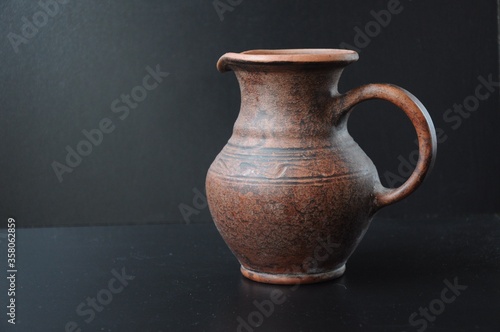 Clay jug with a pattern backlit on a black background
