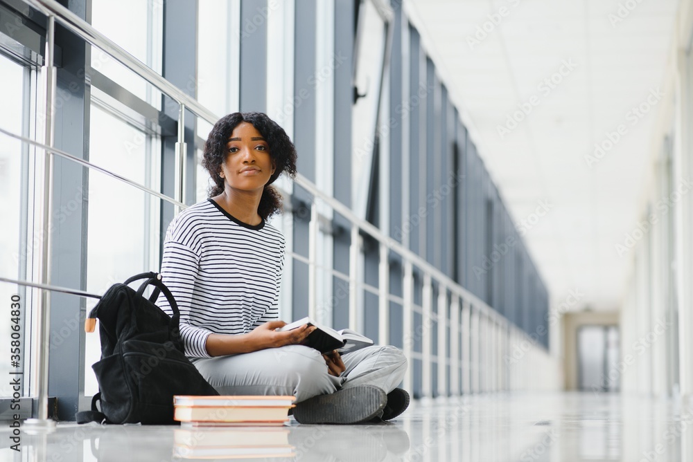 Portrait of african female college student with curly black hair in bright corridor Portrait of african female college student with curly black hair in bright corridor