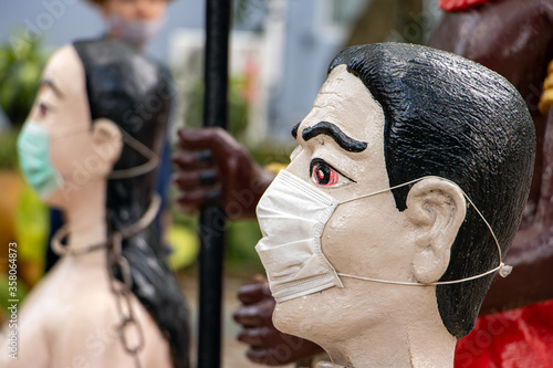Fotografie The portrait of Thai pair with face mask in the Buddhist hell, Wat​ Muang​ temple​ located​ Ang​ Thong and Ayutthaya​ during coronavirus pandemic, Thailand