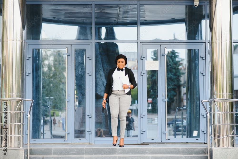 Happy successful professional posing near office building. Young African American business woman standing outside. Female business leader concept