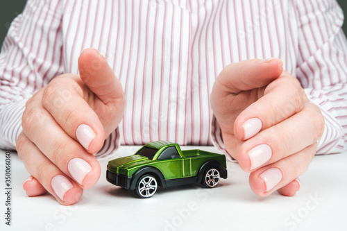 Orenburg, Russia - May 5, 2020: green toy car in female hands, protection and property insurance concept