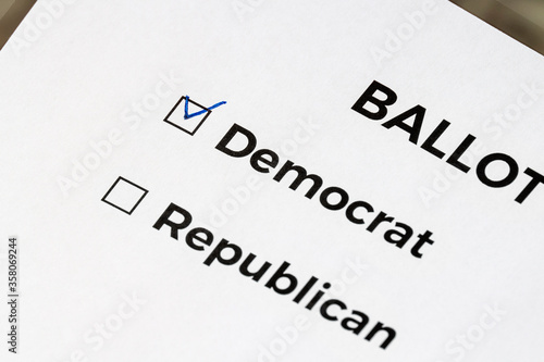Checklist concept. Closeup of ballot paper with words Democrat and Republican and a pen on it. A checkmark for Democrat in the checkbox.