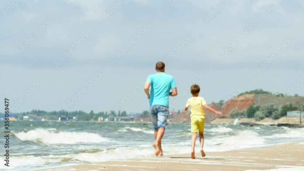 Family Run On Sea Shore. Father and Son Having Fun, Playing Chasing, Jogging on the Beach at Summer Vacation Family Run On Sea Shore. Father and Son Having Fun, Playing Chasing, Jogging on the Beach at Summer Vacation