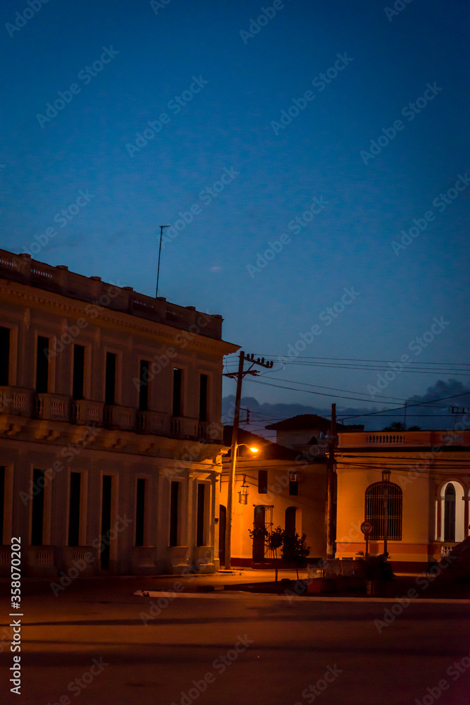 Fototapeta premium Atmospheric Central square with Spanish colonial style buildings and illuminated street lamp, Remedios, Cuba