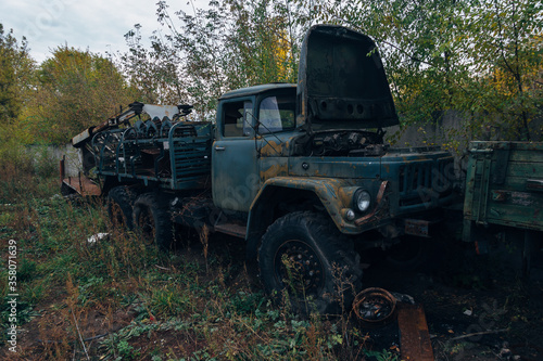 Old rusty truck at abandoned overgrown industrial area