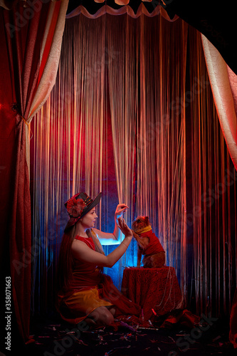 Beautiful girl model training a small dog on the theater stage. Photo shoot in the circus style
