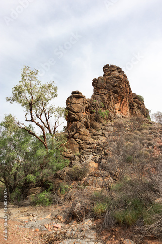 Corroboree rock: sacred Australian aboriginal rock, near Alice Springs. Vertical flat formation, orange colors. Vertical picture. WestMacdonnell ranges, Northern Territory NT, Australia, Oceania