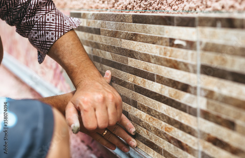 Master tiler glues  wall  tiles. Concept of the  contruction.