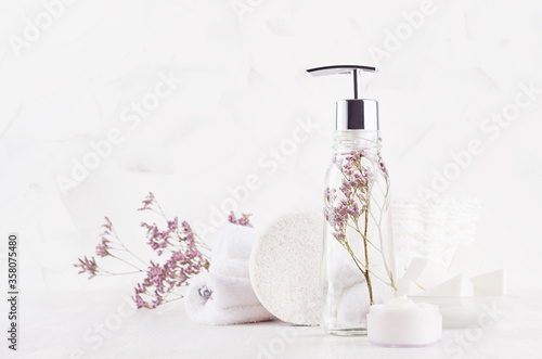 Elegant white cosmetic products and accessories for bathing and spa in soft light white interior with copy space.