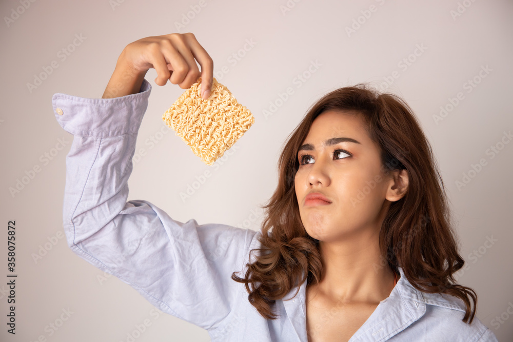 Φωτογραφία unhappy, sad girl looking up, having instant noodle; concept of cheap budget fas