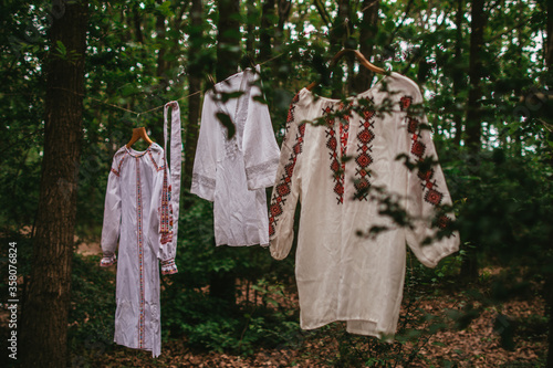 White Ukrainian national embroidered shirts hanging on a rope in the forest