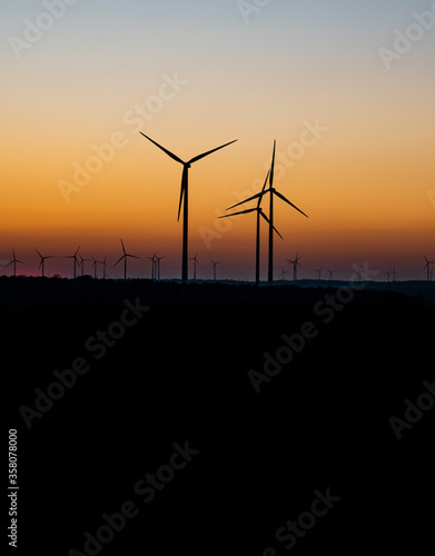 Black Silhouette of windturbines energy generator on amazing sunset at a wind farm in germany