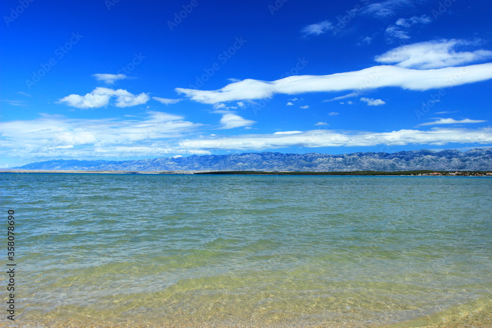 Sandy beach in Nin, Croatia. Velebit mountain, blue sky and white clouds in background. Sandy beach in Nin, Croatia. Velebit mountain, blue sky and white clouds in background.