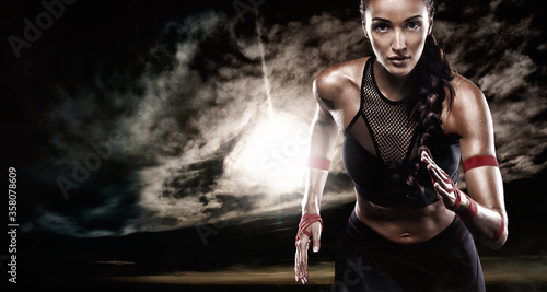 Strong athletic woman sprinter, running on dark background wearing in sportswear. Fitness and sport motivation. Runner concept.