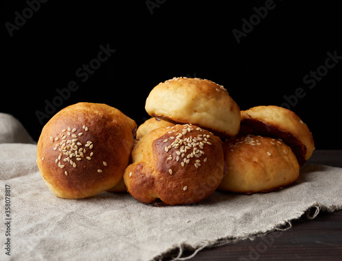 baked round bun with sesame seeds, black background