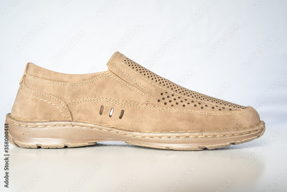 Men's beige leather shoes, models moccasins. Photographed close-up on a light background. Men's beige leather shoes, models moccasins. Photographed close-up on a light background.