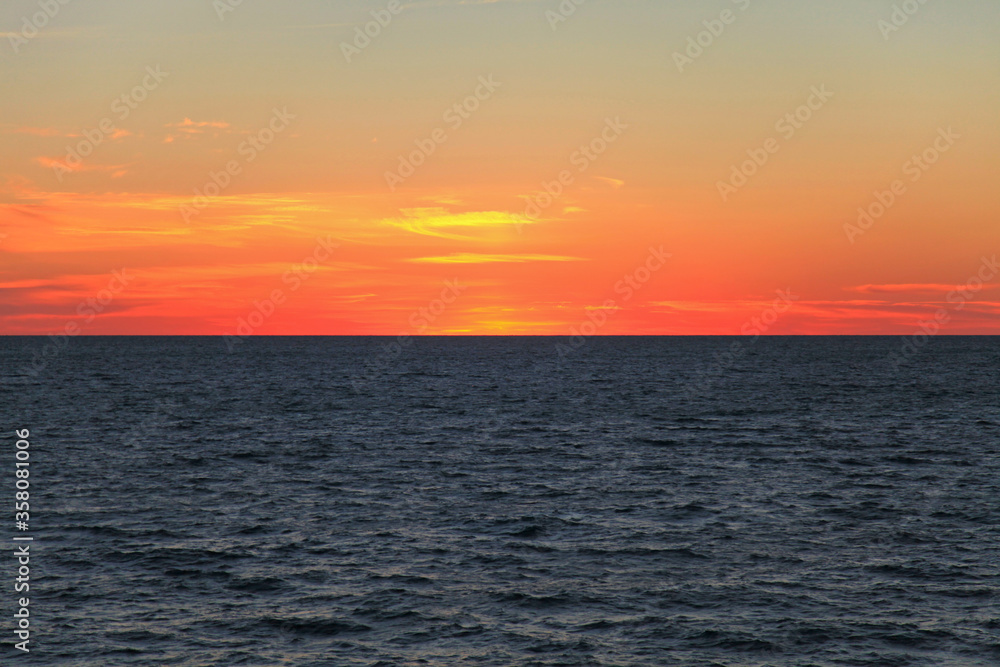 Morning on the high seas. Dark water and scarlet sky before sunrise. Seascape and background. Endless sea horizon, sadness and romance. Minutes of silence over the sea surface