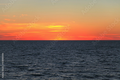 Morning on the high seas. Dark water and scarlet sky before sunrise. Seascape and background. Endless sea horizon, sadness and romance. Minutes of silence over the sea surface