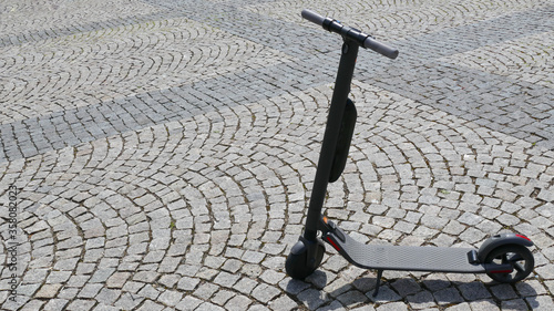 Electric scooter parked on cobblestones in the city center.