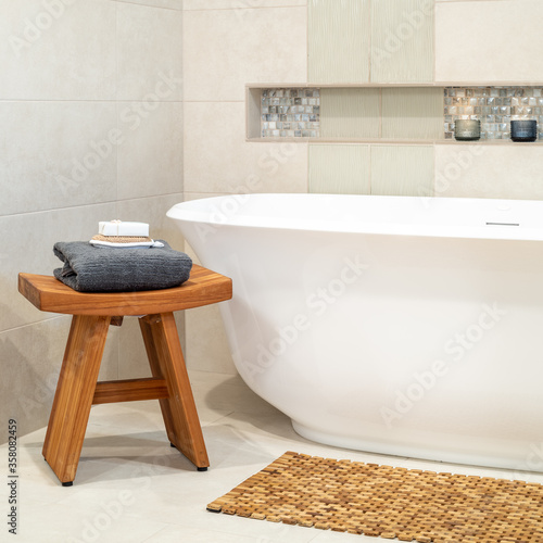 Serene inviting freestanding bath with wooden stool and lit candles