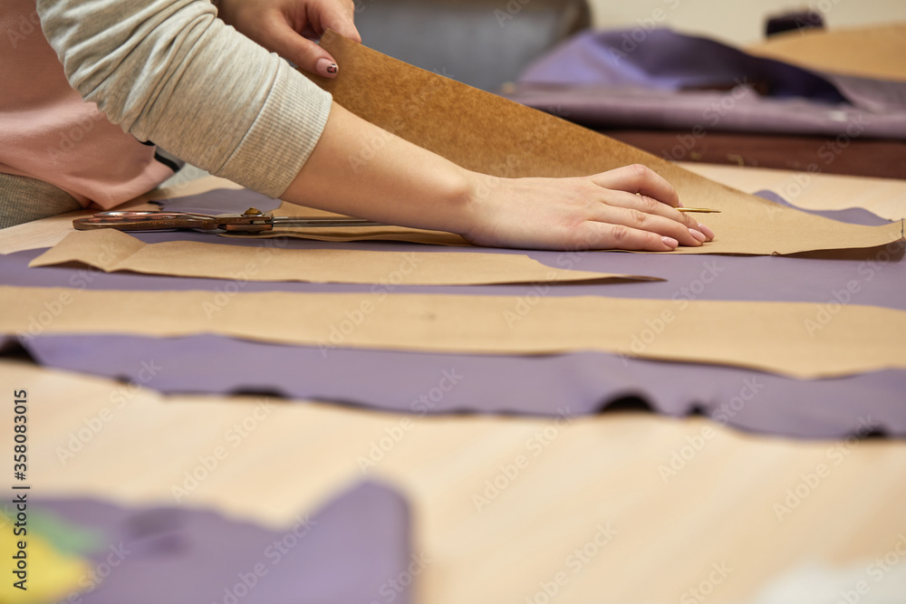 Tailor woman is working at table in atelier Tailor woman is working at table in atelier