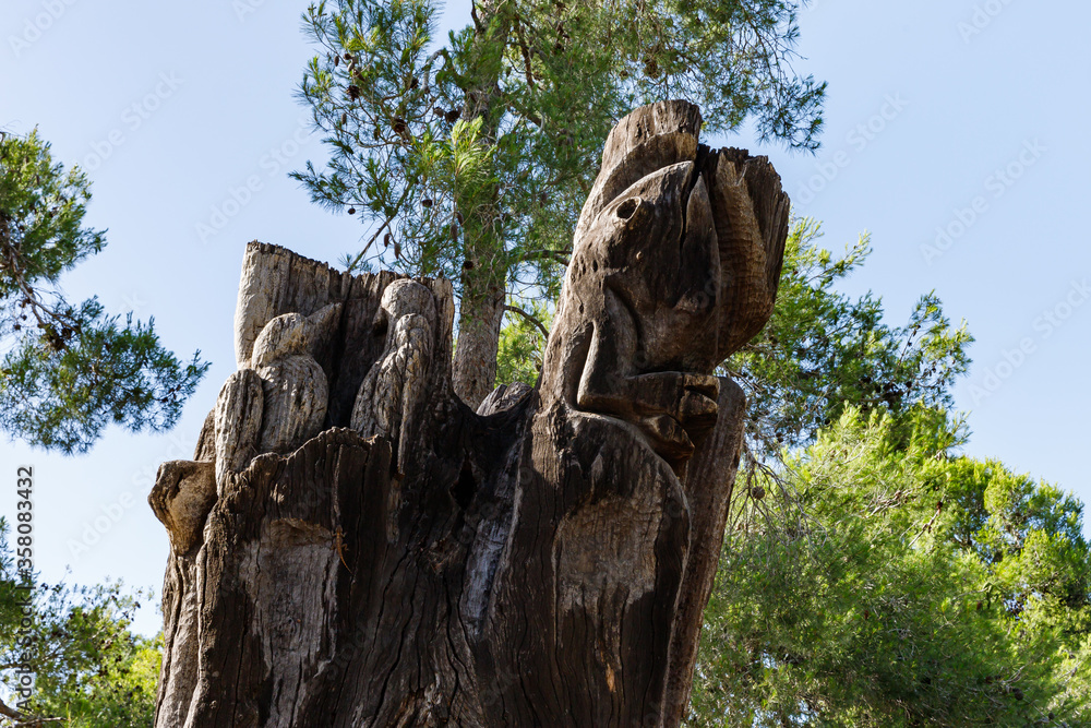 Remains of an old dry tree with birds and a lizard carved on a trunk in the Totem park in the forest near the villages of Har Adar and Abu Ghosh