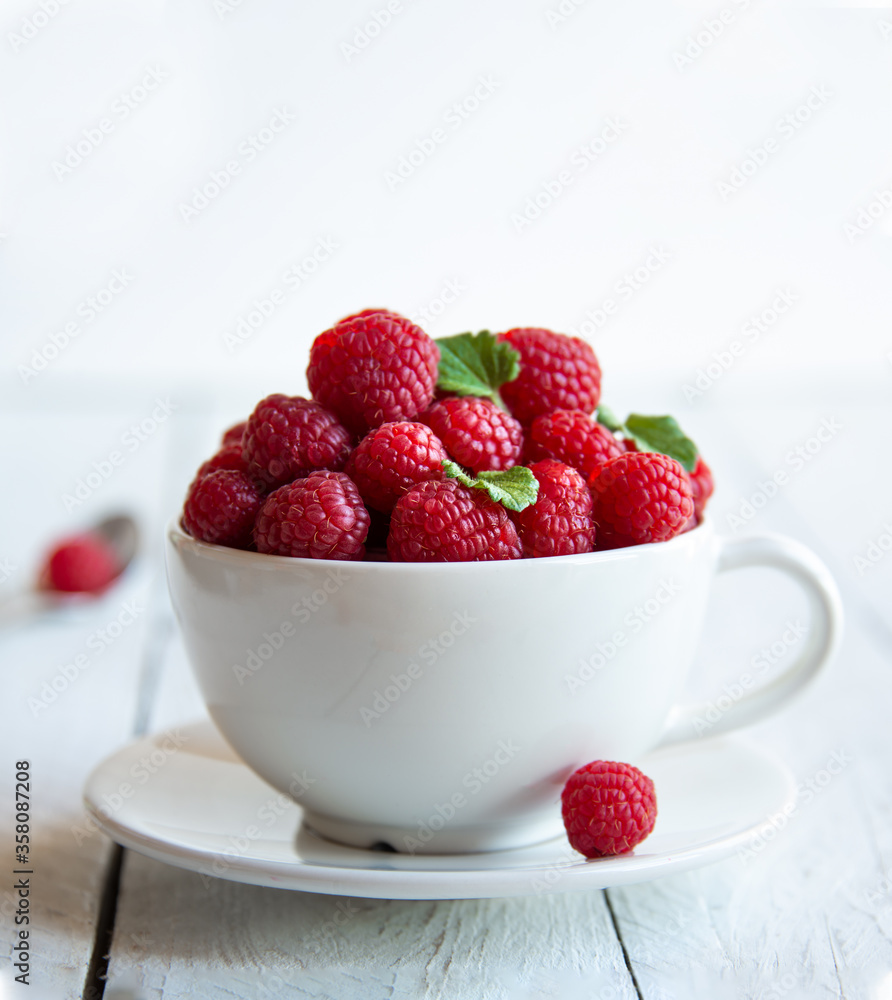 Fresh raspberries with leaves in white cup Fresh raspberries with leaves in white cup