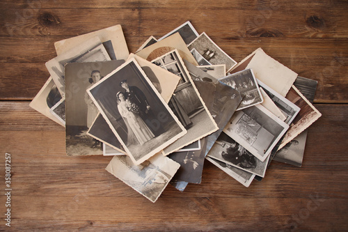 old vintage monochrome photographs in sepia color are scattered on a wooden table, the concept of genealogy, the memory of ancestors, family ties, memories of childhood photo