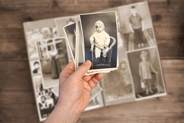 old man’s male hands hold old retro family photos over an album with vintage monochrome photographs in sepia color, the concept of genealogy, memory of ancestors, family ties, childhood memories
