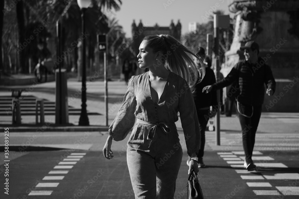 Portrait of young posh elegant woman crossing the road along street. Black and white photo